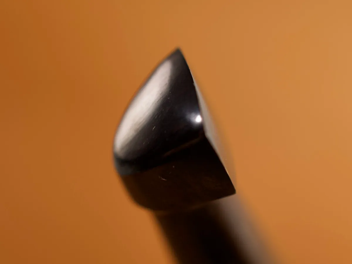 A detailed macro closeup of a beveler leatherworking tool with a smooth leather background.