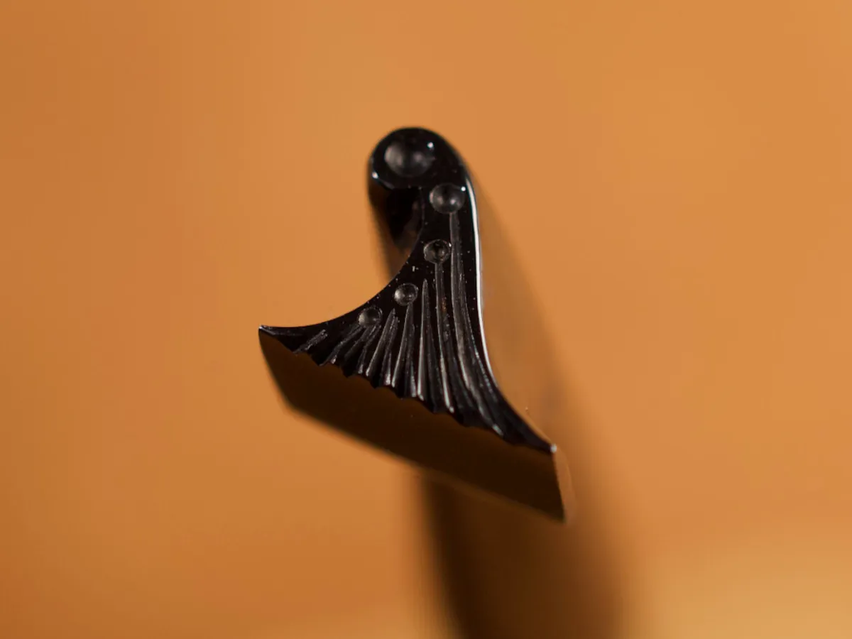 A detailed macro closeup of a border leatherworking tool with a smooth leather background.