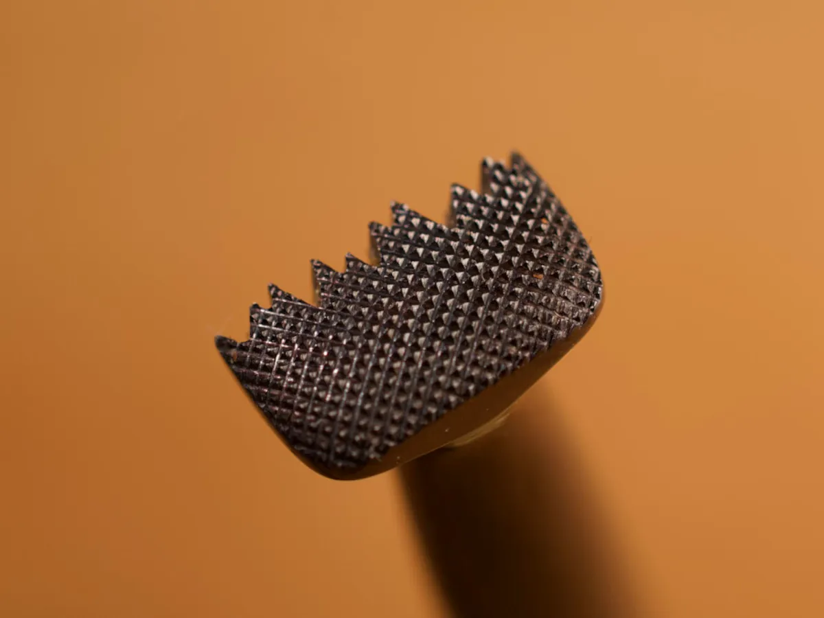 A detailed macro closeup of a figure carving leatherworking tool with a smooth leather background.