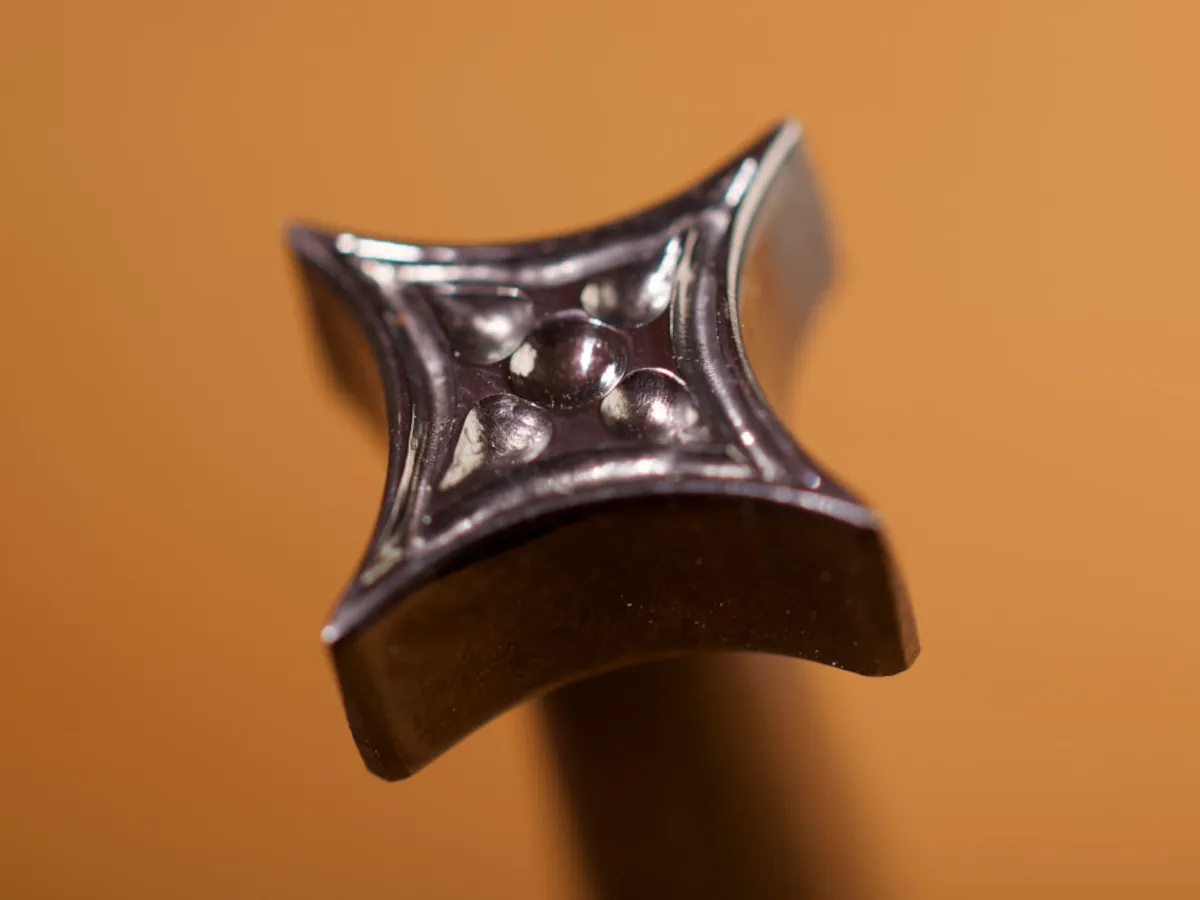 A detailed macro closeup of a geometric leatherworking tool with a smooth leather background.