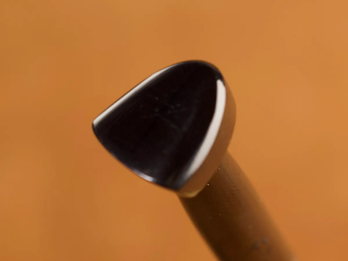 A detailed macro closeup of a matter leatherworking tool with a smooth leather background.