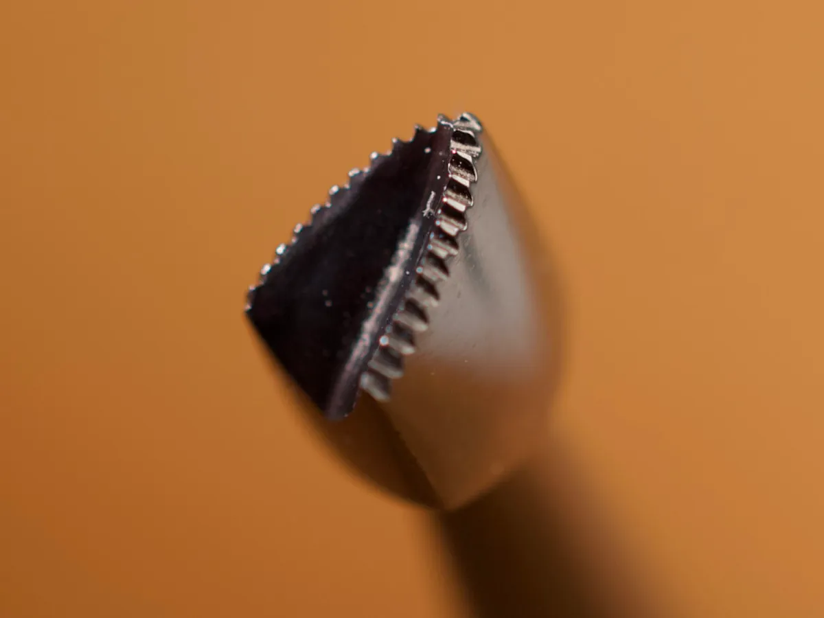 A detailed macro closeup of a mulefoot leatherworking tool with a smooth leather background.